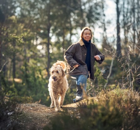 Kvinne og blandingshund på tur i skogen
