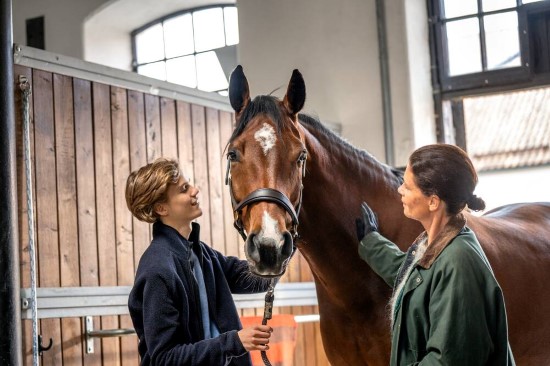 Gutt og mor klapper en hest