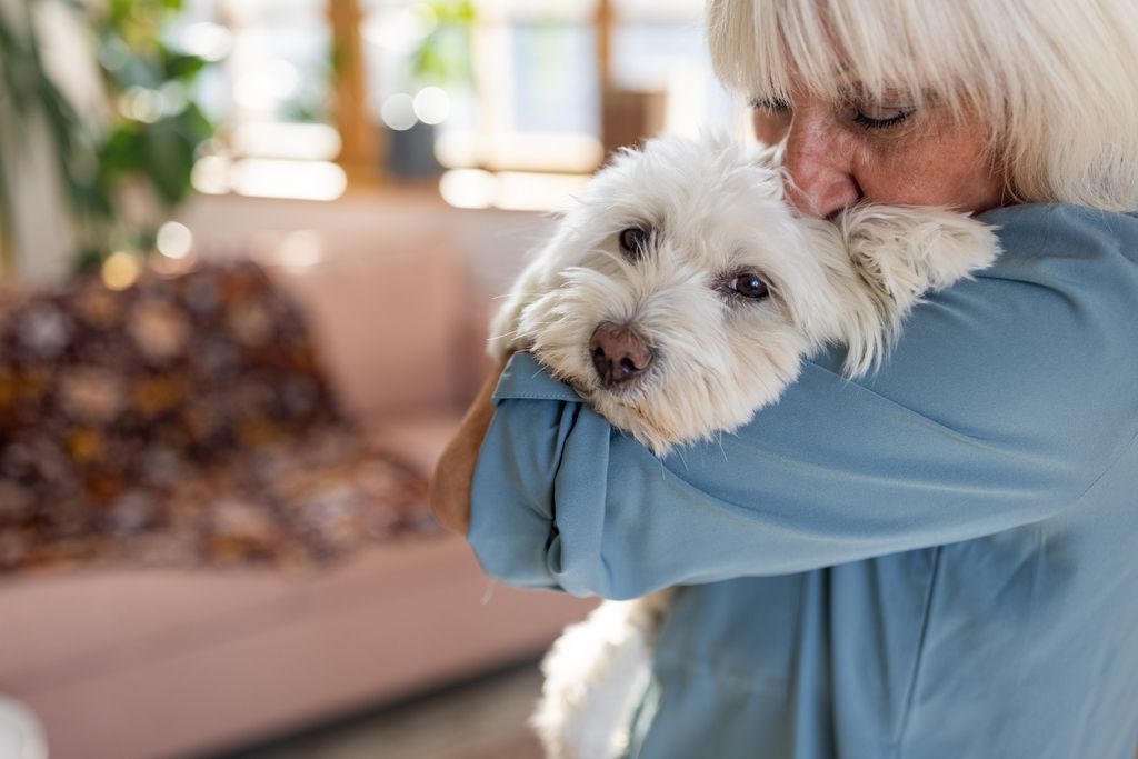 Dame som klemmer en hvit hund