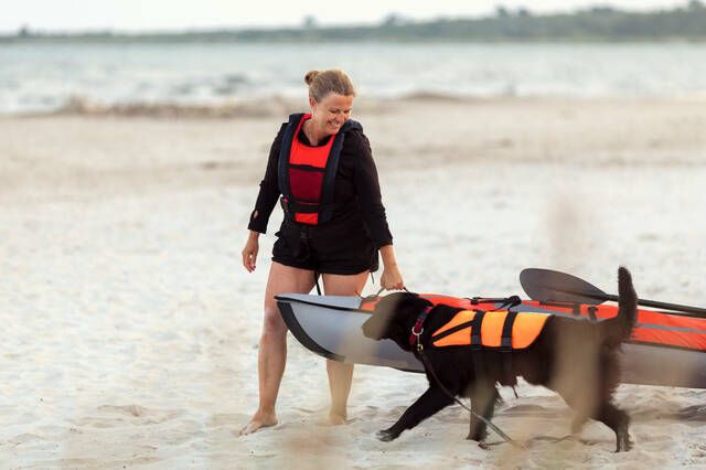 Dame og hund på stranden med kano