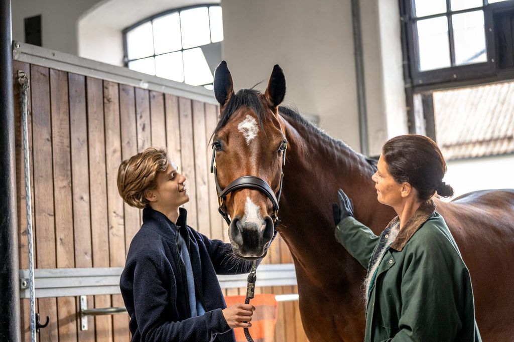 Gutt og dame står med en hest