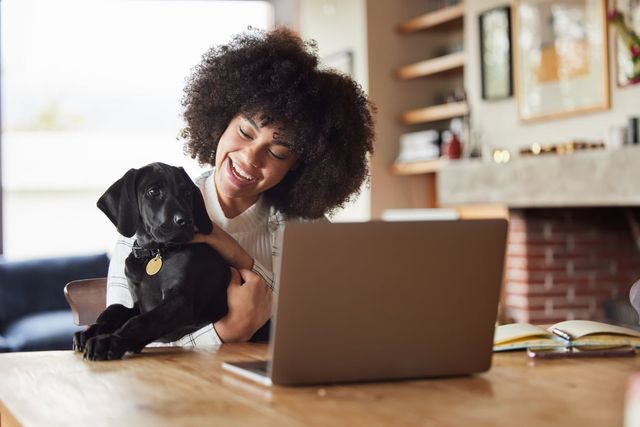 Jente som holder en hund foran PC