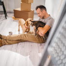 Mann som sitter på gulvet med en hund og en katt