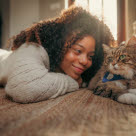 Jente som ligger på gulvet ved siden av en katt