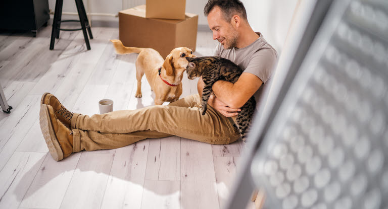 Mann som sitter på gulvet med en hund og en katt