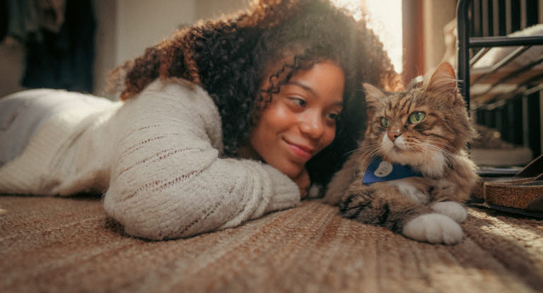 Jente som ligger på gulvet ved siden av en katt