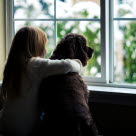 Et barn og en hund som titter ut av vinduet sammen