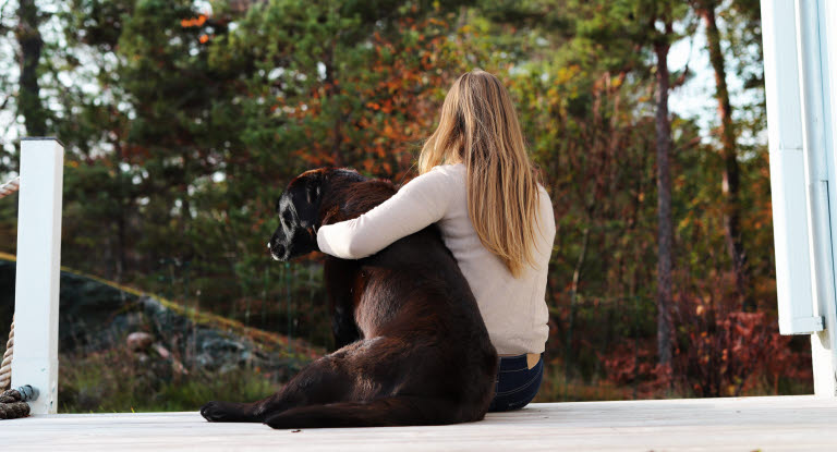 Hund og dame som sitter ute